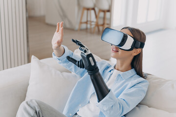 Girl with disability in VR glasses touching objects of virtual reality by bionic prosthetic arm
