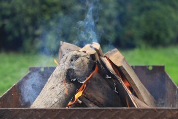 Metal brazier with burning firewood outdoors, closeup