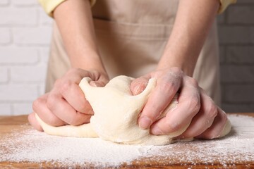 Fototapeta na wymiar Woman kneading dough at wooden table, closeup