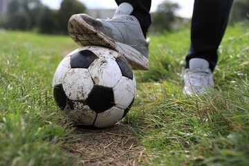 Man with dirty soccer ball outdoors, closeup