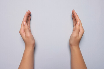 Woman holding on light grey background, closeup of hands. Space for text