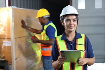 Warehouse workers woman with hardhats and reflective jackets using tablet, walkie talkie radio while looking away and controlling stock and inventory in retail warehouse logistics, distribution center