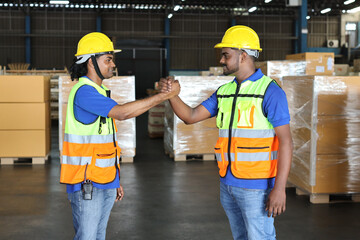 Happy smiling teamwork in hardhats and reflective jackets arm wrestling celebrate successful together completed deal commitment at retail warehouse logistics, distribution center, success concept