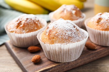 Tasty muffins powdered with sugar on wooden table, closeup