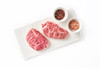 Raw fresh pork cheeks with salt and pepper on a white background