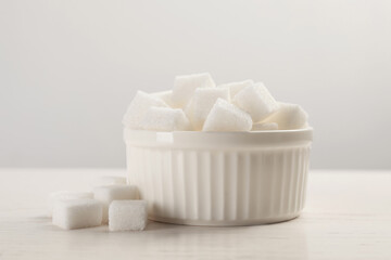 Bowl with sugar cubes served on white table
