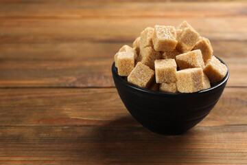 Brown sugar cubes on wooden table, space for text