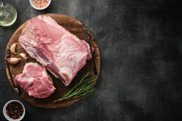 Raw pork neck chop meat with herb leaves and spices on wooden board. Grey background. Top view.