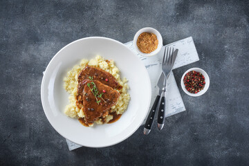 Close up view of sliced roasted beef with mashed potato on plate over grey background. Top view, flat lay. - 535183700