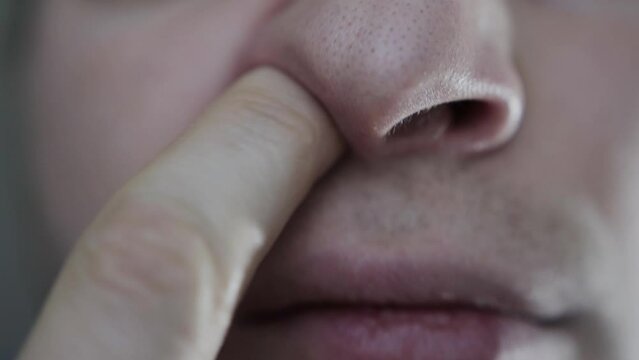 The caucasian man nervously picks his nose with his finger. Psychological habit, close-up