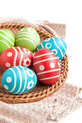 Easter eggs in the wicker plate isolated on white background