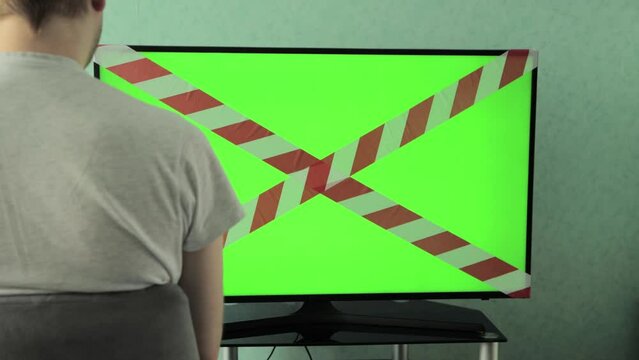 A man watches TV on the screen of which is a forbidden tape. Green screen chrome key. The concept of prohibition and sanctions on television