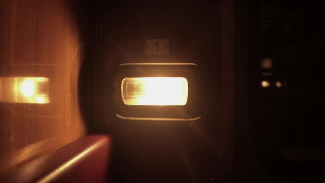 Light from luminaire is lit inside railway passenger train carriage compartment of corridor coach at night. Empty russian railroad wagon. Travel tourism. Nobody, no one. Closeup
