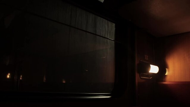 Inside compartment of corridor coach of railway passenger train at night. Light from luminaire is lit inside carriage. City lapms outside window. Empty russian railroad wagon. Travel tourism. Nobody