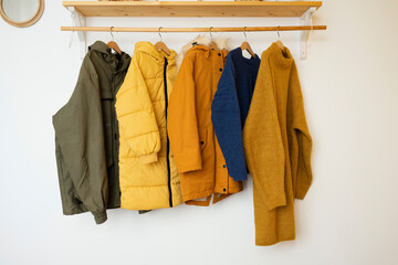 Warm jackets and knitted sweaters hang on wooden hangers in the room