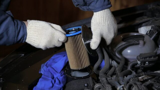 An automobile mechanic removes an old dirty fuel filter from a car. Vehicle fuel system maintenance, close-up