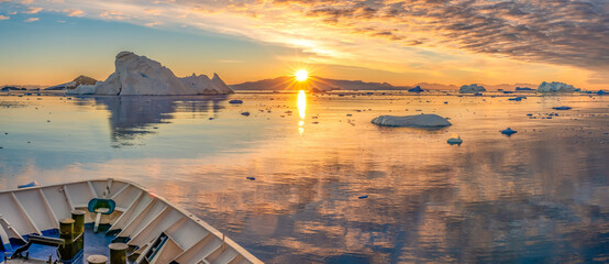 Kreuzfahrtschiff fährt bei einen dramatischer Sonneuntergang / Abendstimmung durch die winterliche...