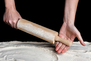 Angry baker hands with rolling pin above flour. Baking concept.