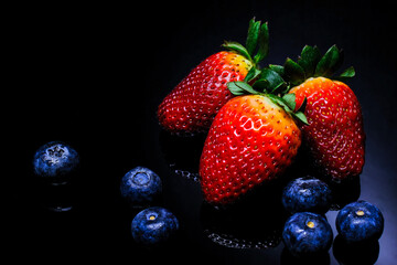 Blueberries and Strawberries on black background, close-up. Selective Focus.