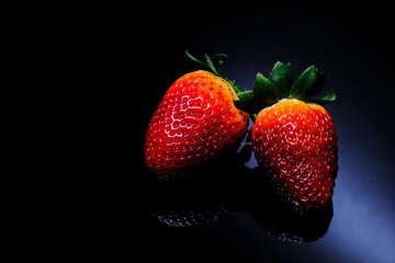 Red strawberries with green leafs, isolated on black background, close-up. Selective Focus.