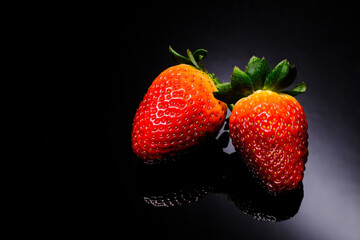 Red strawberries with green leafs, isolated on black background, close-up. Selective Focus.