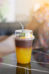 Iced Orange Americano Black Coffee in take away cup (plastic glass) on the table in cafe.