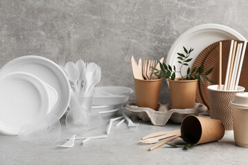 Plastic and eco disposable tableware with green twigs on marble table