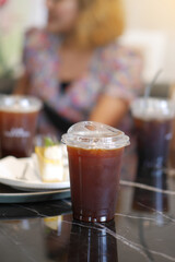 Iced Americano Black Coffee in take away cup (plastic glass) on the table in cafe.