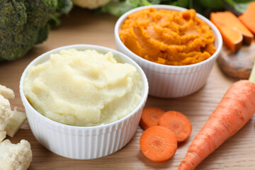 Bowls with tasty puree and ingredients on wooden table, closeup