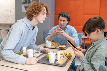 Schoolteacher conversing with two schoolboys at lunch