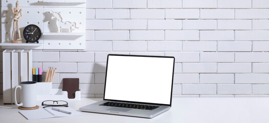 Stylish working desk with laptop computer, books, coffee cup and houseplant.