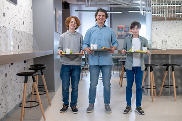 School boys and their teaher having lunch together at school canteen