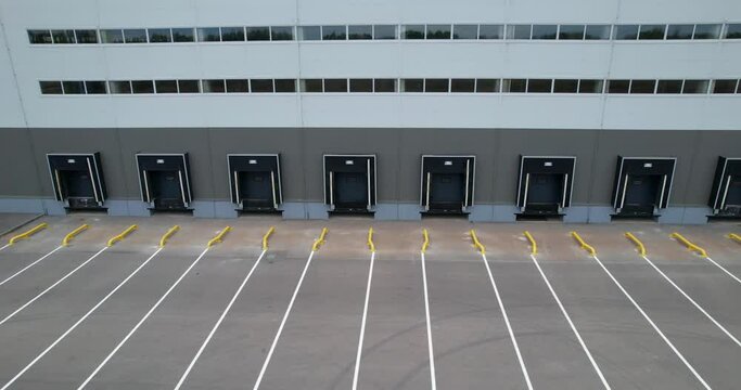 Warehouse gates for loading and unloading cargo in a distributed center. Loading and unloading areas for trucks. The warehouse building is outside. Aerial view