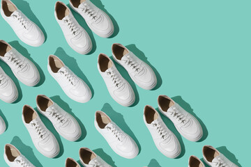 White sneakers pattern on a mint blue background. The shoes are comfortable and casual. Background for a shoe store. A pair of new sneaker shoes.