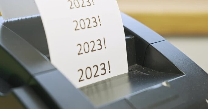 Receipt printer prints text: 2023. Close-up, side view. Concept of holidays, new year, christmas, new stage, promotions, sales in stores. Tear off the check