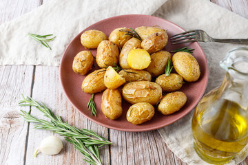 Fresh baked small whole potatoes with olive oil, rosemary and garlic on vintage red plate