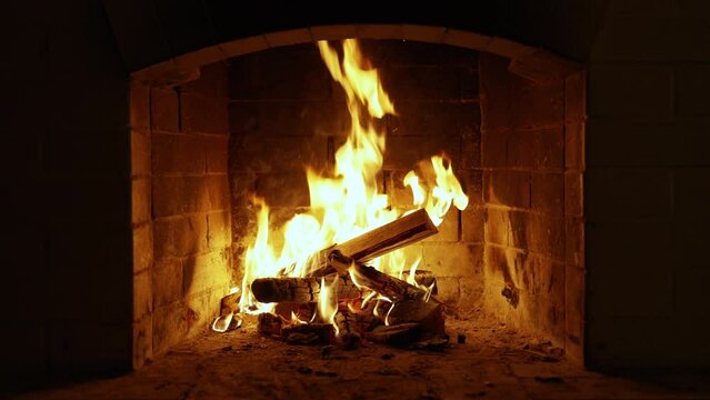 A Glowing Fire in the Stone Fireplace Warm Cozy Fireplace with Real Wood Burning in it Winter and Christmas Holidays Concept Slow Motion. UHD TV screen saver. Video for meditation.