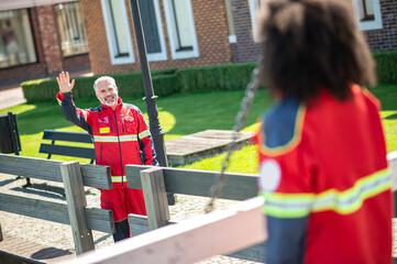 Joyous paramedical professional greeting a coworker outdoors