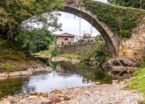 Ancient arch bridge over the river and abundant green vegetation