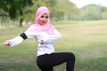 Public exercise lifestyle concept, fitness woman listening music from wireless earphones and mobile phone.  Athletic young asian girl in muslim sportswear standing, stretching after workout