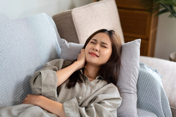Female employee is lying on the couch and touching the neck pain while feeling stressed and disappointed