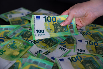 Fan of paper Euro bills in female hands. Euro cash background on banknotes, fan of 100 euros, one hundred euros