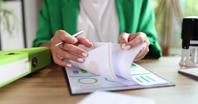 A woman with a pen flips through documents