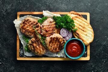 Barbecue: grilled meatballs wrapped in bacon with spices and sauce. On a stone board. Top view.