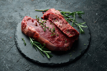 Fototapeta na wymiar Aged juicy striploin steak. Meat. On a black stone background. Side view.