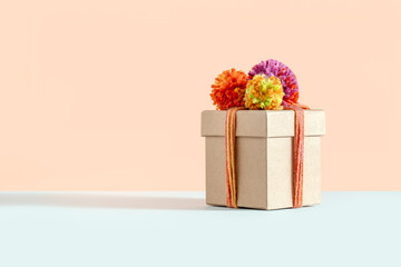 Minimal eco friendly gift box packaging on beige background. Sustainable fashion delivery, giveaway concept. Winter birthday present, Christmas aesthetic. Reusable package with pink, orange yarn bow.