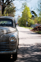 Obraz na płótnie Canvas Fragment of an old passenger car on a suburban road. An old rusty automobile. Selective focus.