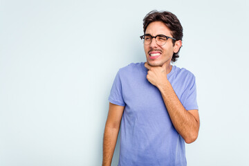 Young hispanic man isolated on blue background touching back of head, thinking and making a choice.