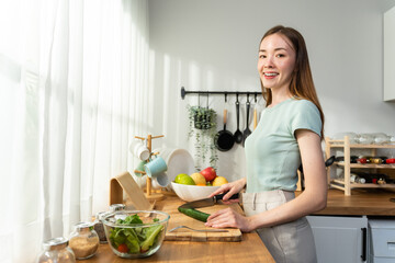 Young Caucasian attractive woman cook green salad in kitchen at home. 