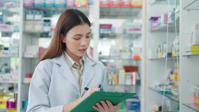 Professional woman pharmacist checking products in drugstore using noteboard.